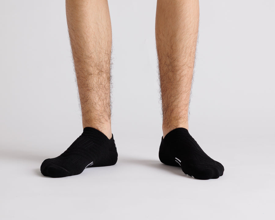 Black no-show grip socks worn on both feet, viewed from the front. By Squid Socks.