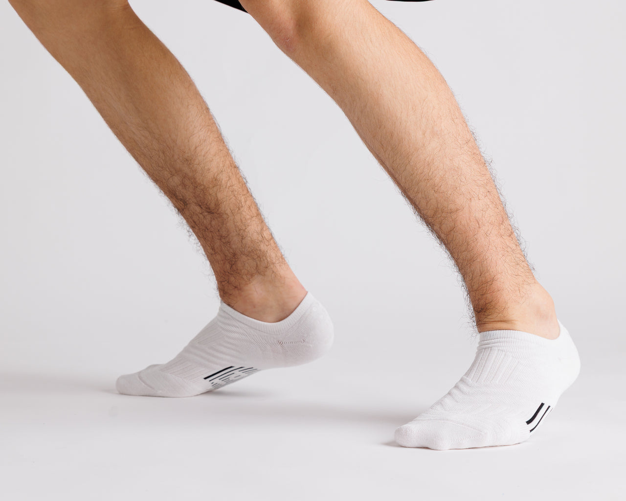 White no-show grip socks worn with heels raised, showing side views. By Squid Socks.