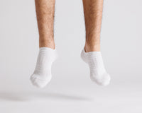 Thumbnail for White no-show grip socks worn on both feet, lifted above the floor. By Squid Socks.