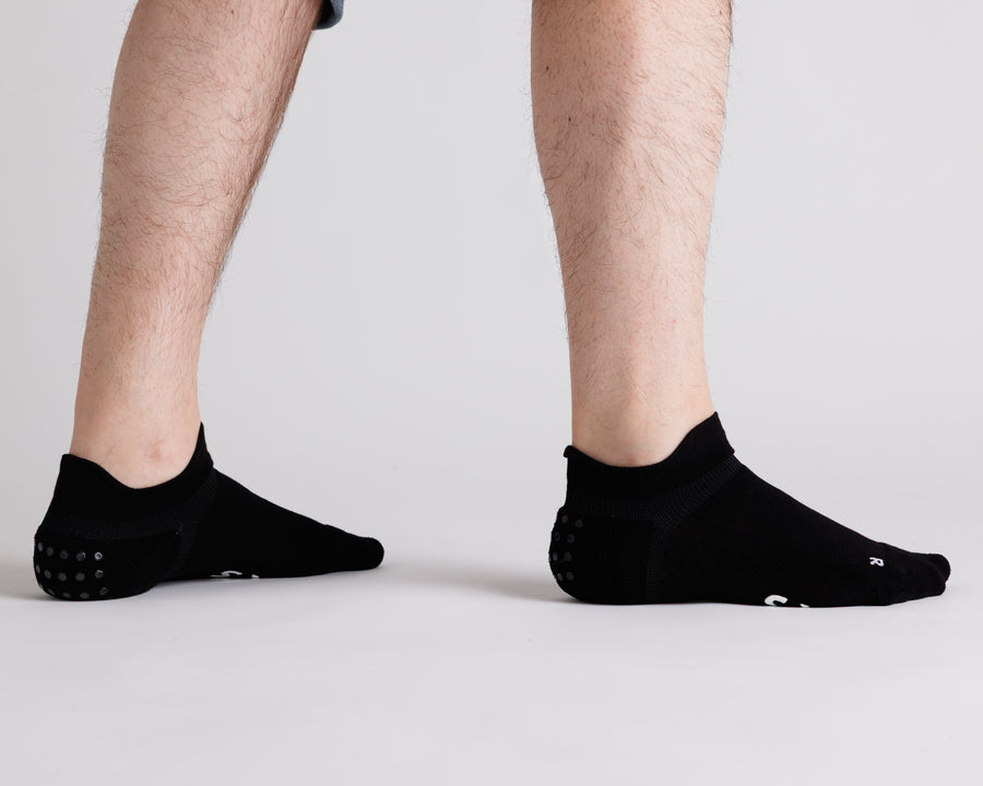 Black ankle grip socks viewed from behind, showing heel tabs and heel grip dots. By Squid Socks.