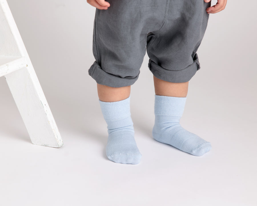 Casen kids socks: child standing in pale blue socks. Squid Socks, the brand seen on Shark Tank.