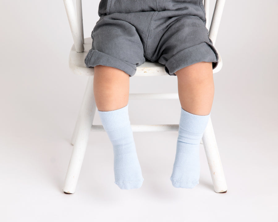 Casen kids socks: child seated on a chair wearing pale blue socks. Squid Socks, the brand seen on Shark Tank.