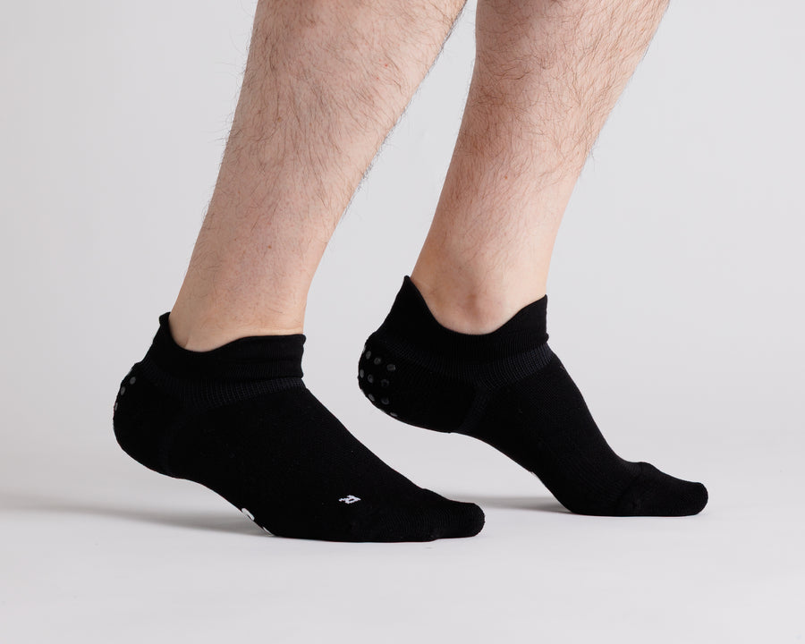 Black ankle grip socks worn with heels raised, showing side views and heel tabs. By Squid Socks.