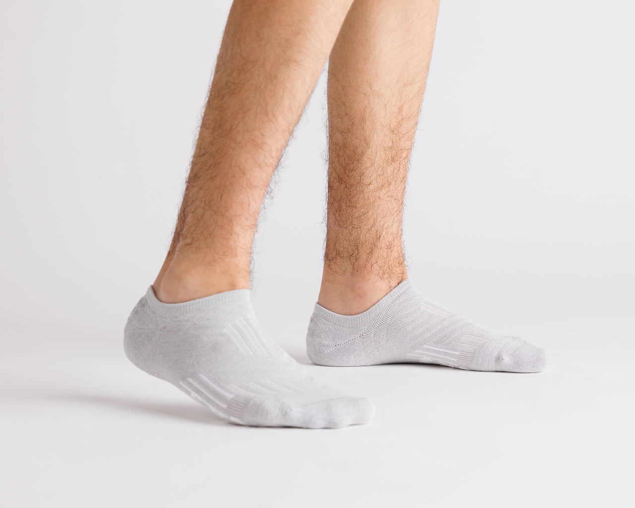 Gray no-show grip socks worn with heels raised, showing side views. By Squid Socks.