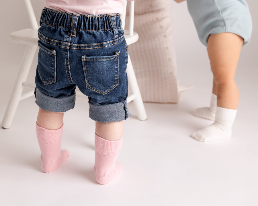 Claire kids socks: child standing in soft pink socks beside another child. Squid Socks, the brand seen on Shark Tank.