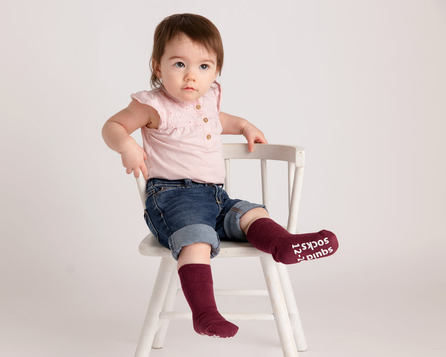 Courtney cotton crew socks: child seated on a chair wearing burgundy crew socks. Squid Socks, the brand seen on Shark Tank.