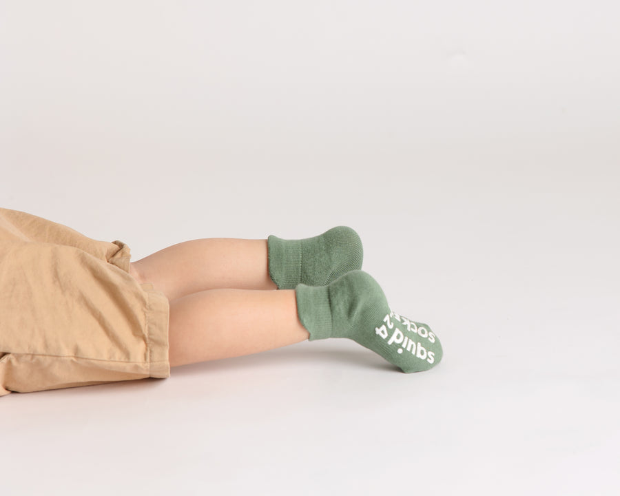 Chai ankle socks: child lying down wearing sage green ankle socks. Squid Socks, the brand seen on Shark Tank.