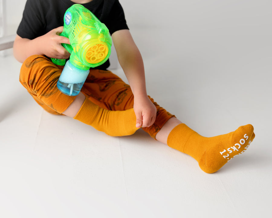 Camden cotton crew socks: child playing with a toy in mustard crew socks. Squid Socks, the brand seen on Shark Tank.