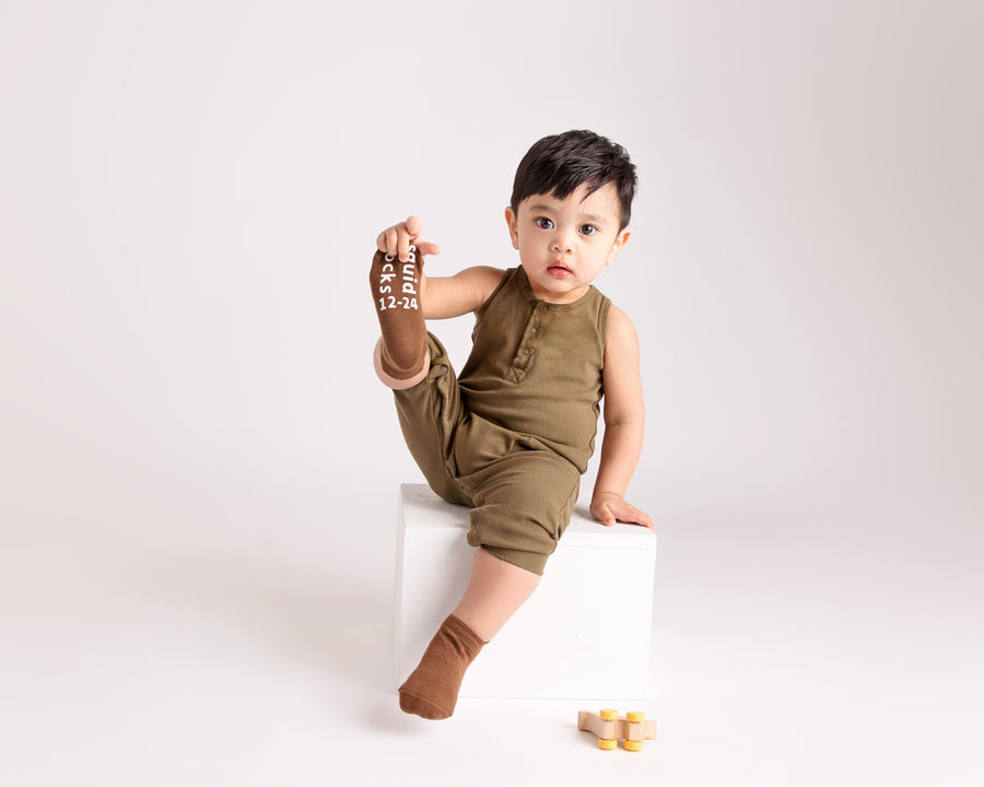 Chai ankle socks: child seated showing a brown sock sole. Squid Socks, the brand seen on Shark Tank.