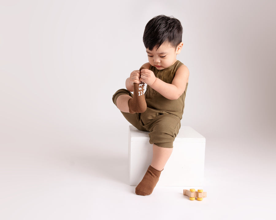Chai ankle socks: child seated on a block wearing brown ankle socks. Squid Socks, the brand seen on Shark Tank.
