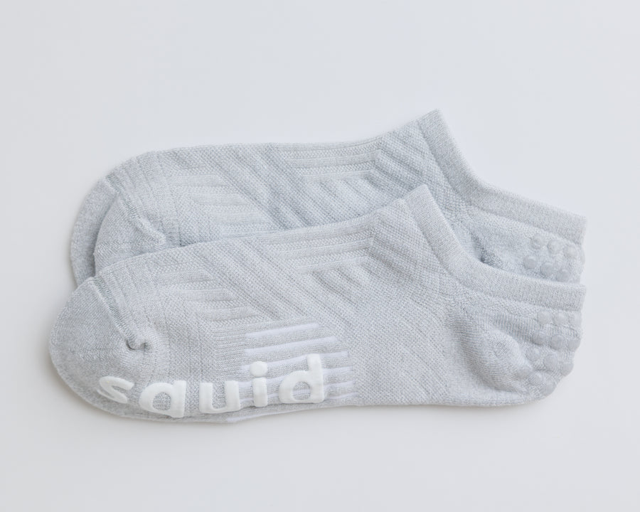 One pair of gray no-show grip socks laid together, showing knit panels and white bottom grips. By Squid Socks.