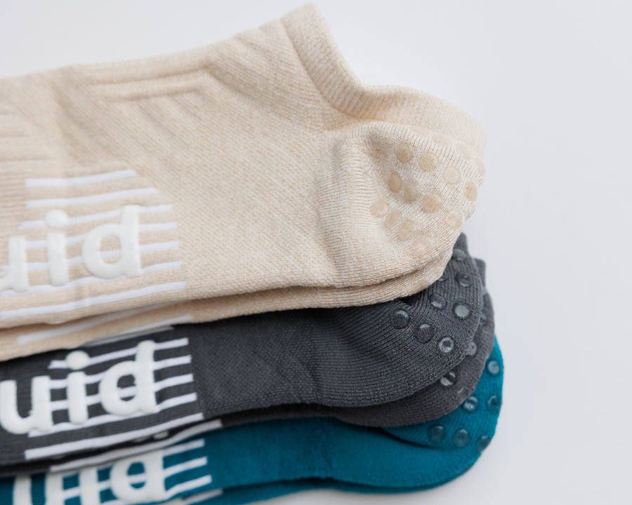 Close-up of stacked Driftline no-show socks showing heel grip dots and white bottom grips. By Squid Socks.