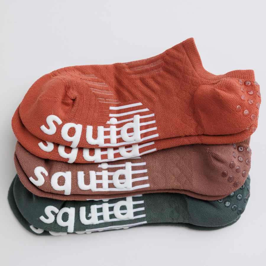 Earthbound no-show grip socks in terracotta, brown, and muted green, stacked to show all three colors. By Squid Socks.