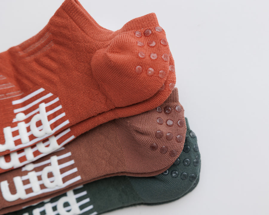 Close-up of stacked Earthbound no-show socks showing heel grip dots and white bottom grips. By Squid Socks.