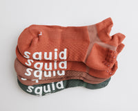 Earthbound ankle grip socks in terracotta, brown, and muted green, stacked to show all three colors. By Squid Socks.