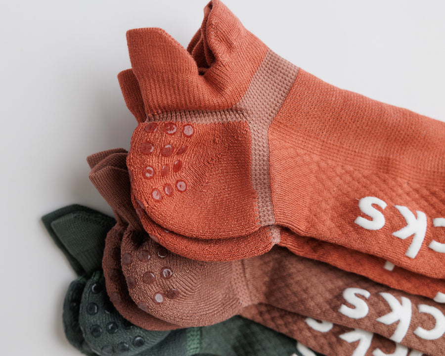 Close-up of stacked Earthbound ankle socks showing heel grip dots and contrasting knit panels. By Squid Socks.