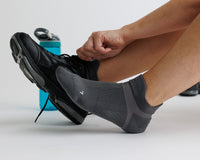 Thumbnail for Person wearing charcoal gray ankle grip socks while tying a black athletic shoe. By Squid Socks.