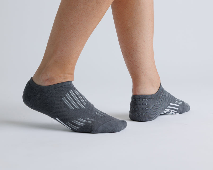 Charcoal gray no-show grip socks worn with heels raised, showing side views. By Squid Socks.