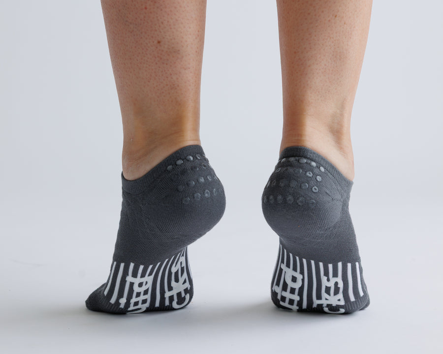 Charcoal gray no-show grip socks viewed from behind, showing heel and bottom grips. By Squid Socks.