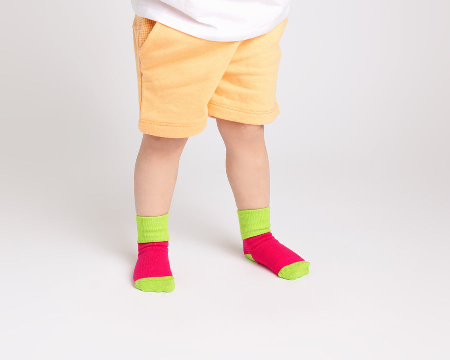 CeCe kids socks: child standing in pink socks with neon green cuffs. Squid Socks, the brand seen on Shark Tank.
