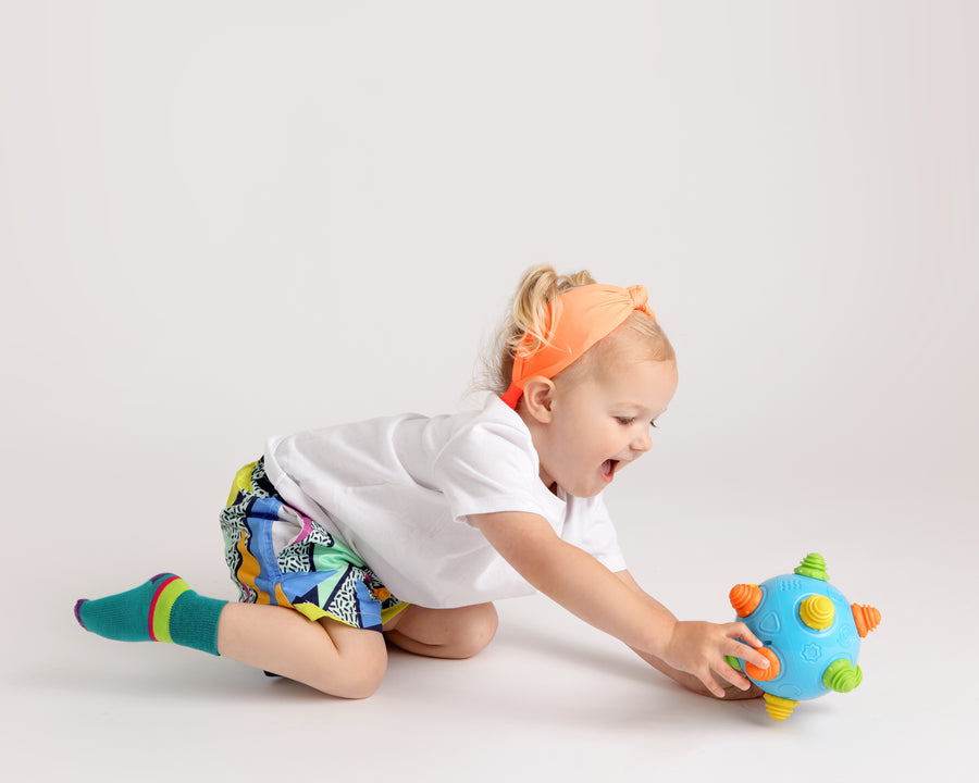 CeCe kids socks: child reaching for a toy in teal socks. Squid Socks, the brand seen on Shark Tank.