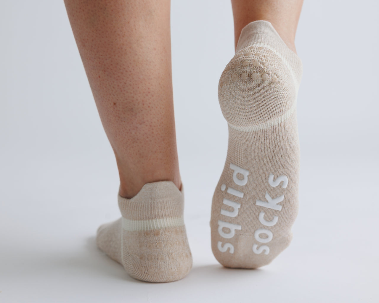 Beige ankle grip socks with one sole raised to show white bottom grips. By Squid Socks.