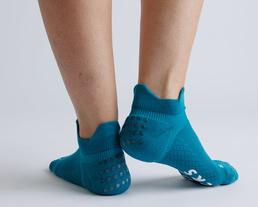 Teal ankle grip socks viewed from behind, showing heel tabs and grip dots. By Squid Socks.