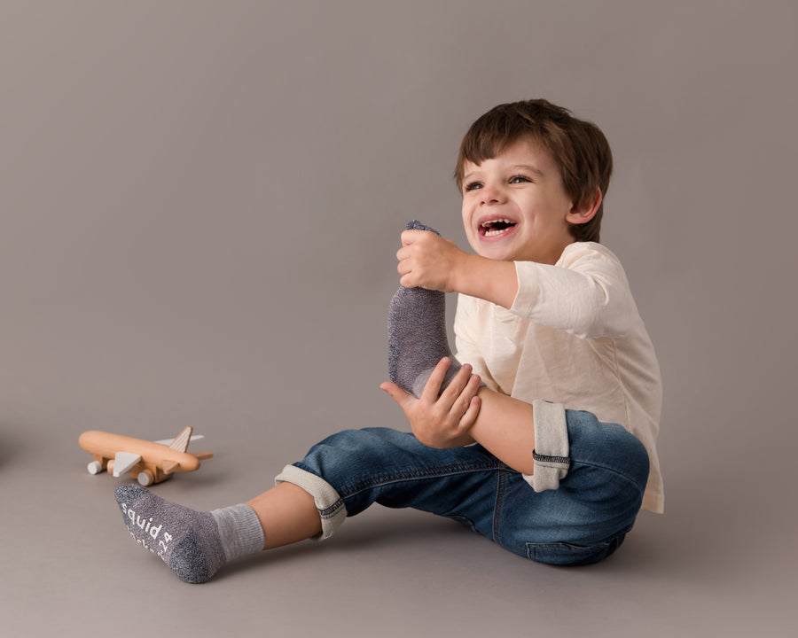Caelan cotton crew socks: child seated holding a socked foot. Squid Socks, the brand seen on Shark Tank.