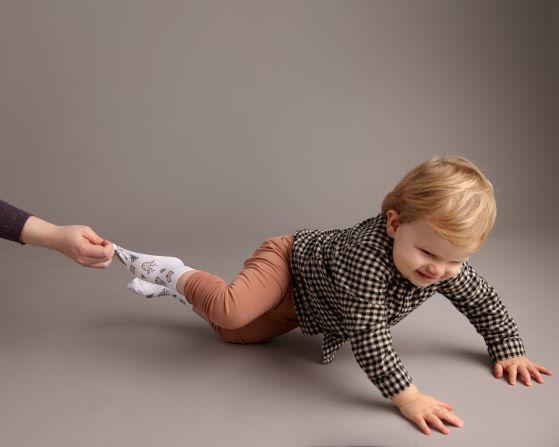 Camping kids socks: adult gently pulling a sock while a child crawls. Squid Socks, the brand seen on Shark Tank.
