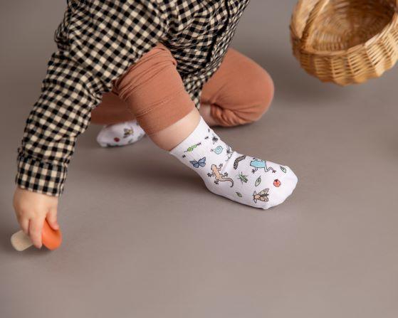 Camping kids socks: child seated wearing camping-print socks. Squid Socks, the brand seen on Shark Tank.