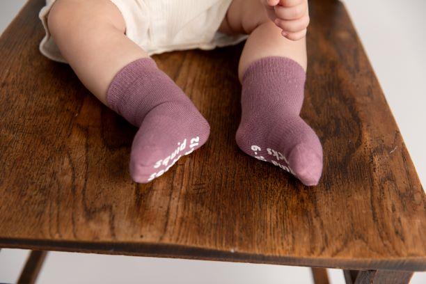 Cami kids socks: baby wearing lavender socks on a wooden surface. Squid Socks, the brand seen on Shark Tank.