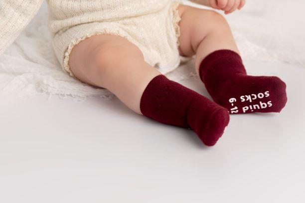 Channing kids socks: baby wearing wine-colored socks with sole grips visible. Squid Socks, the brand seen on Shark Tank.