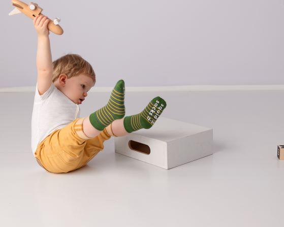 Colin kids socks: child playing with a toy in green striped socks. Squid Socks, the brand seen on Shark Tank.