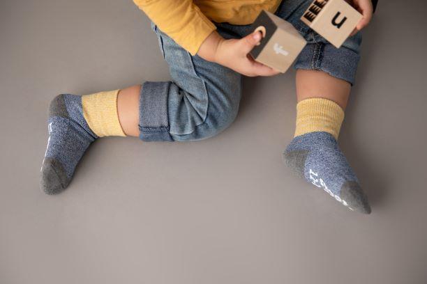 Chris cotton crew socks: child playing with blocks in yellow-cuff crew socks. Squid Socks, the brand seen on Shark Tank.