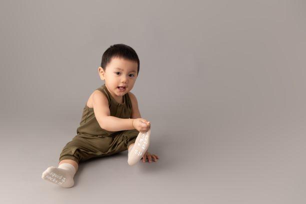 Classic kids socks: child seated wearing sand-colored socks. Squid Socks, the brand seen on Shark Tank.