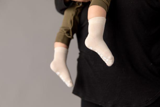 Classic kids socks: child being held while wearing sand-colored socks. Squid Socks, the brand seen on Shark Tank.