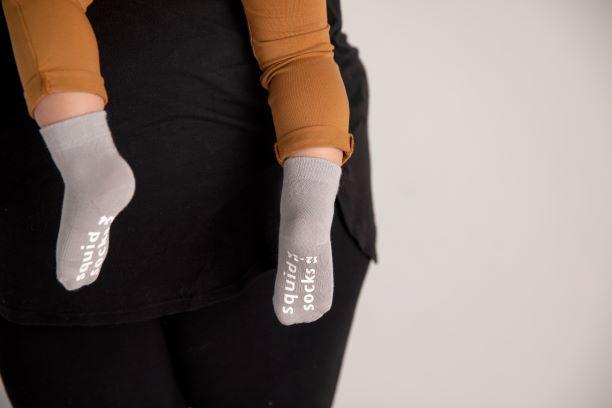 Classic kids socks: child being held while wearing light gray socks. Squid Socks, the brand seen on Shark Tank.