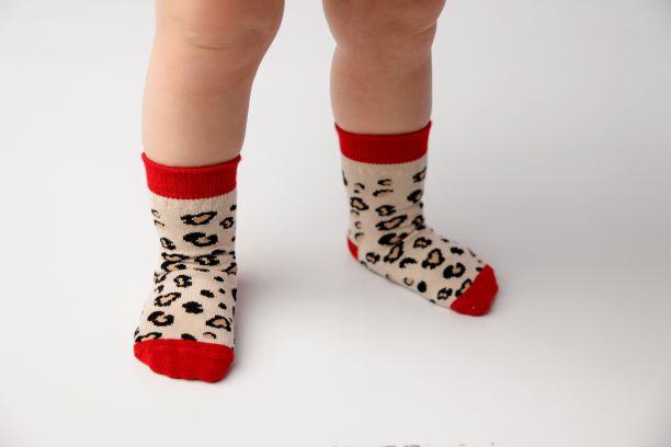 Chanel kids socks: child standing in red-cuff leopard socks. Squid Socks, the brand seen on Shark Tank.
