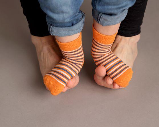 Colin kids socks: adult holding a child's feet in orange striped socks. Squid Socks, the brand seen on Shark Tank.