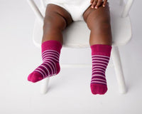 Christina kids socks: baby seated wearing magenta striped socks. Squid Socks, the brand seen on Shark Tank.
