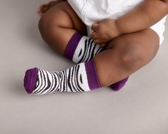 Chanel kids socks: baby seated wearing purple zebra-print socks. Squid Socks, the brand seen on Shark Tank.