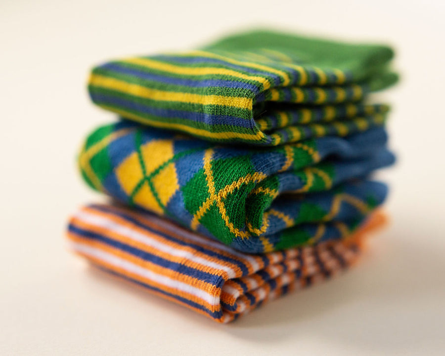 Colin kids socks: stack of green striped, blue argyle and orange striped socks. Squid Socks, the brand seen on Shark Tank.
