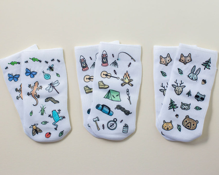 Camping kids socks: three white socks with bugs, camping gear and woodland animal prints. Squid Socks, the brand seen on Shark Tank.