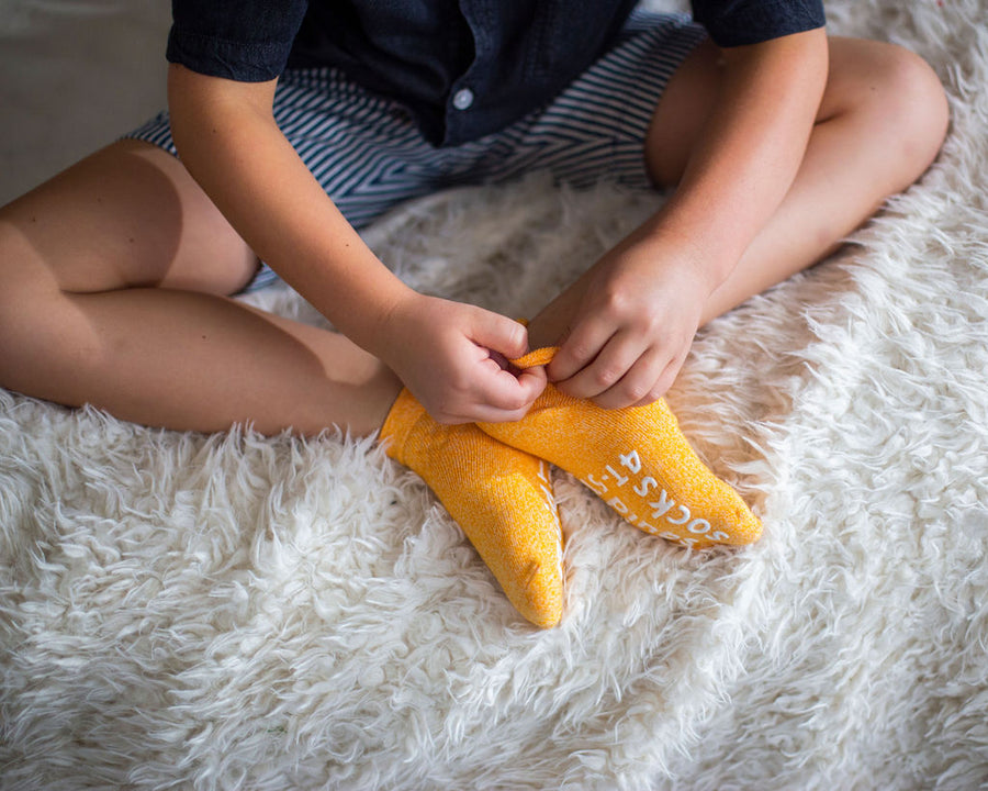 Chevy ankle socks: child adjusting orange ankle socks. Squid Socks, the brand seen on Shark Tank.