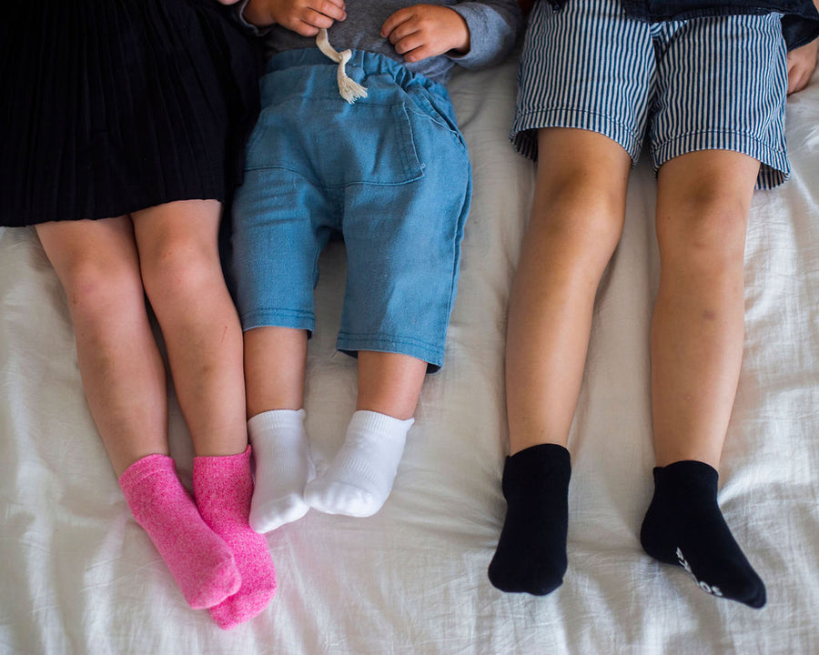 Crew ankle socks: three children seated wearing pink, white and black ankle socks. Squid Socks, the brand seen on Shark Tank.