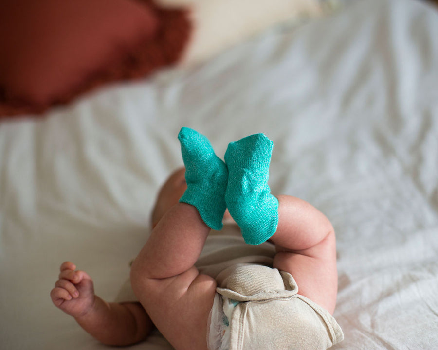 Clarissa ankle socks: baby lying down wearing teal ankle socks. Squid Socks, the brand seen on Shark Tank.
