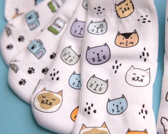 Meow kids socks: close-up of colorful cat faces on white socks. Squid Socks, the brand seen on Shark Tank.