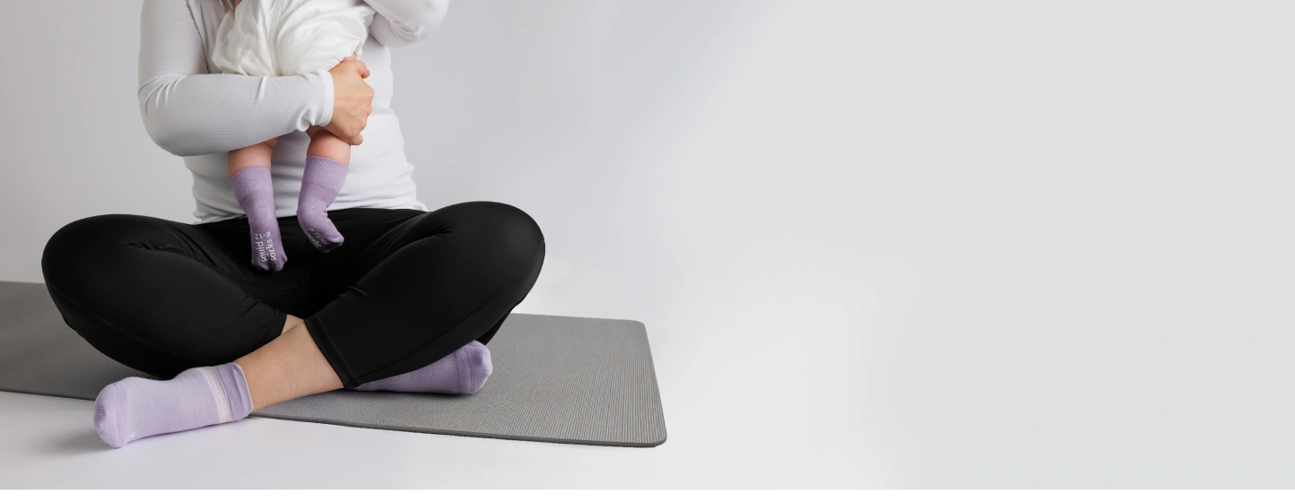 A seated parent and baby wearing purple socks