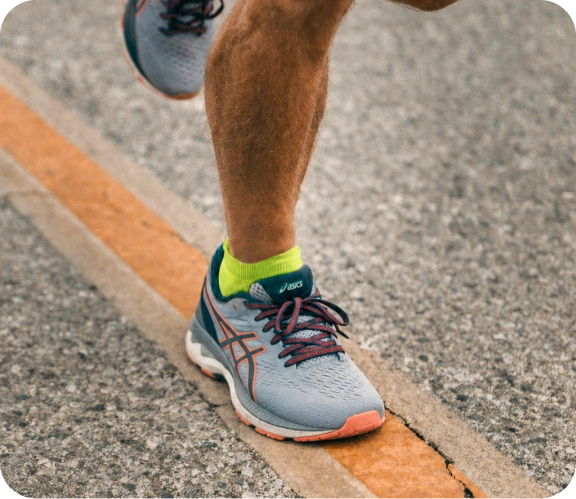 Adult tying a running shoe while wearing teal Squid Socks ankle grip socks.